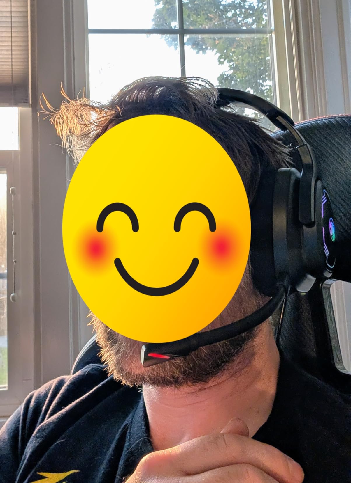 Person wearing the black IMYB A36 headset at a desk by a window with the microphone near the chin, face covered by a smiley graphic